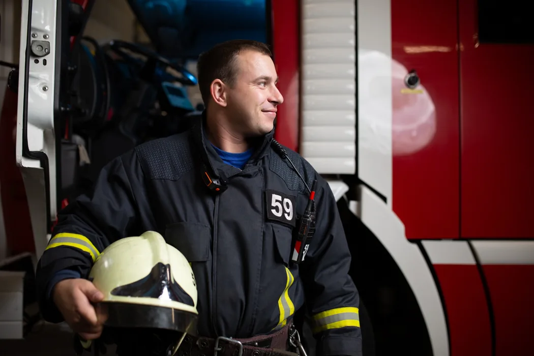 Symbolfoto: Feuerwehrmitglied bei einem Einsatzfahrzeug